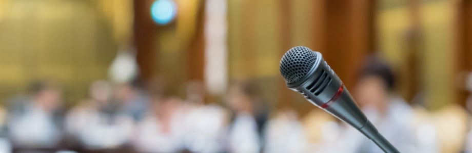 a microphone with a blurred background of people in a meeting room