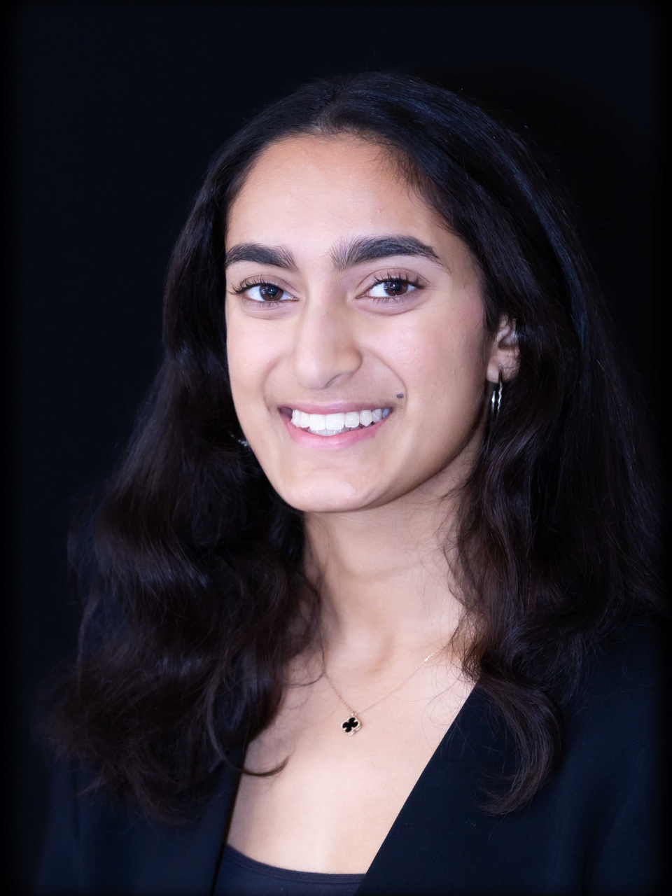 Young woman with dark hair, thick eyebrows, and wearing black